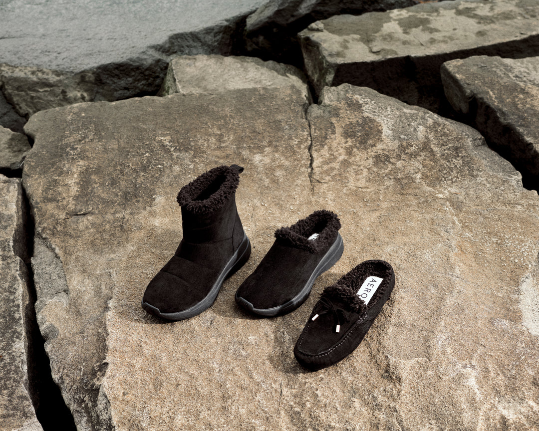 Black slip-on shoes and boots on a stone surface